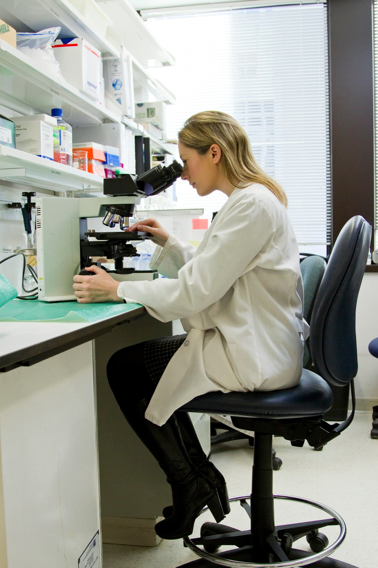 A researcher reviewing documents at a desk in a modern biotech laboratory